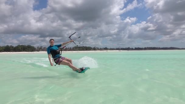 Movimiento lento: Smiling surfer girl kitesurf más allá de la cámara en la laguna azul — Vídeo de stock