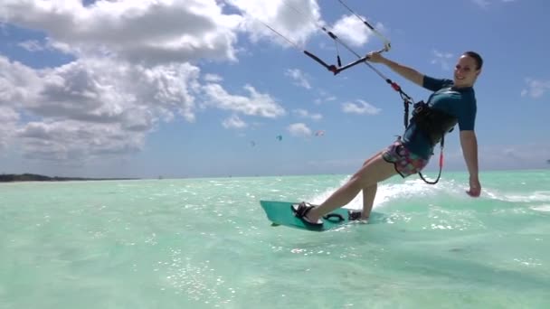 Lassú mozgás: Boldog fiatal szörfös lány kiteboarding tökéletes kék óceán — Stock videók