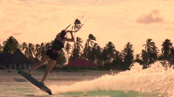 Closeup câmera lenta: Extreme kiter garota kiteboard pulando rali ao pôr do sol dourado — Vídeo de Stock