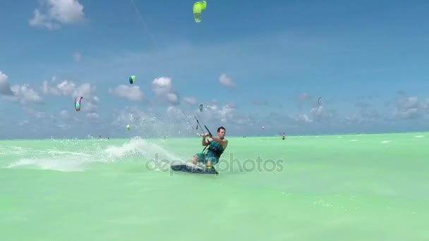 Slow Motion: Happy extreme kiter springen en opspattend water druppels in camera — Stockvideo