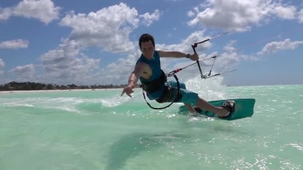 Lassú mozgás: Boldog mosolygó kite szörfös kiteboarding, és bemutatja a surf shaka jele — Stock videók