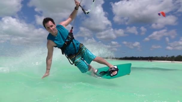 Ağır çekim yakın çekim: Mutlu gülümseyen uçurtma sörfçü kiteboarding tropikal lagün içinde — Stok video