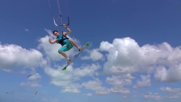 Movimiento lento: Kite surfista extrema feliz saltando por encima de la cámara, mostrando el signo de shaka — Vídeo de stock