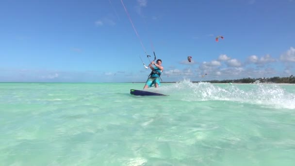 Ağır çekim: Mutlu gülümseyen sörfçü eğlenir tropikal mavi lagün kiteboarding — Stok video