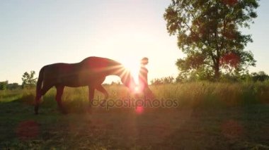 Yakın: Büyük aygır at bir yolda bir kızla günbatımında otlatılması