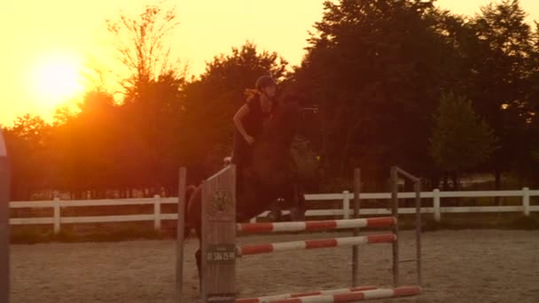 SLOW MOTION : Entraînement de cavalière sautant dans le centre équestre au coucher du soleil — Video