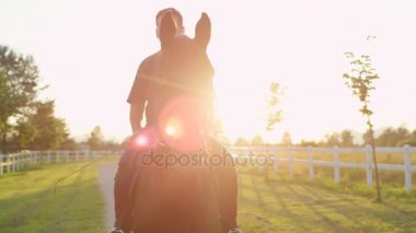 Yakın: güçlü atın üzerinde oturanbir ve gündoğumu zaman zevk üst düzey kovboy