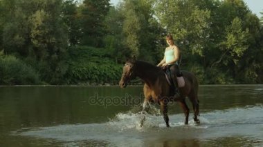 Ağır çekim: genç kız binici binicilik sığ nehir gülümseyen