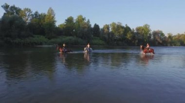Yakın: ata binerek ve nehre güneşli günde duran üç kız