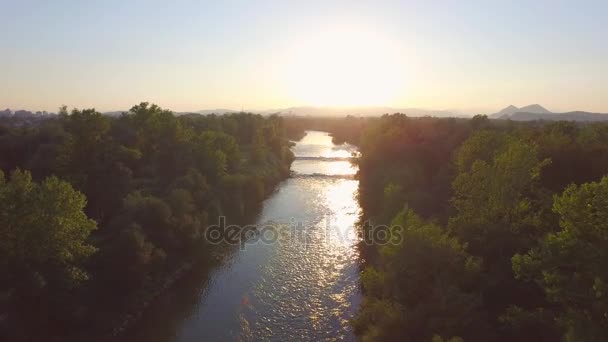 AÉRIEN : Coucher de soleil doré magique sur une large rivière à courant rapide avec fond rocheux 