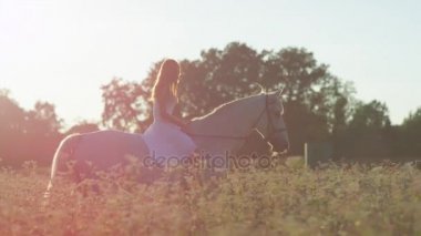 Ağır çekim: Beyaz elbise sürme at Pembe çiçek açan içinde alan kız gülümseyerek