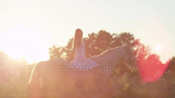 CLOSE UP: Красива дівчина верхи на коні без очей у квітковому полі на заході сонця — стокове відео