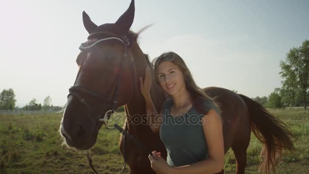 CERRAR: Retrato de una chica sonriente acariciando y besando su gran caballo marrón — Vídeo de stock