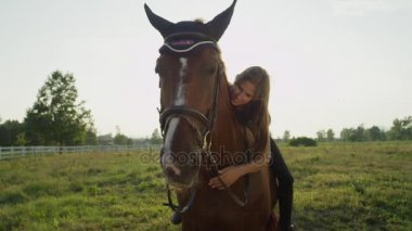 Yakın: at üzerinde oturan ve onu sarılma genç beyaz esmer güzel kız