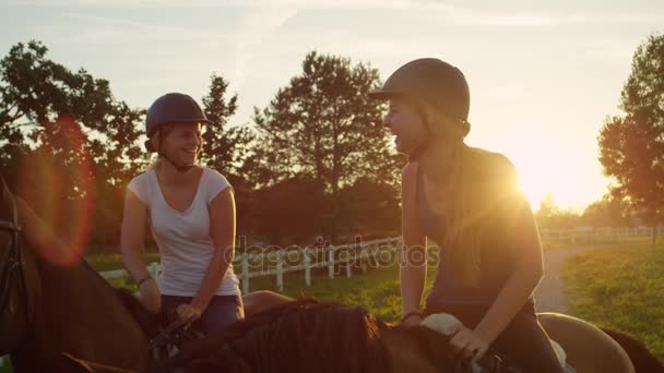 Movimiento lento: Dos hermosas niñas felices disfrutando de paseo a caballo al atardecer — Vídeo de stock