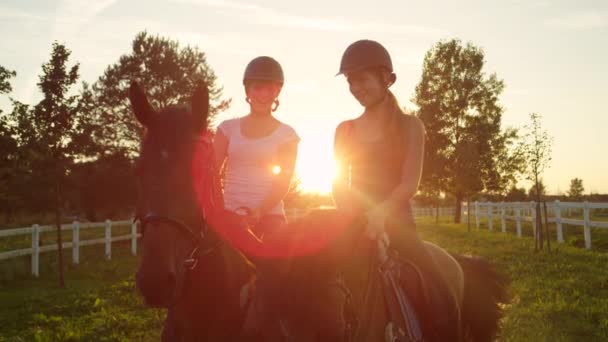 スローモーション: 2 つの馬を楽しんでいる若い女の子の笑顔は魔法の夕日に乗る — ストック動画