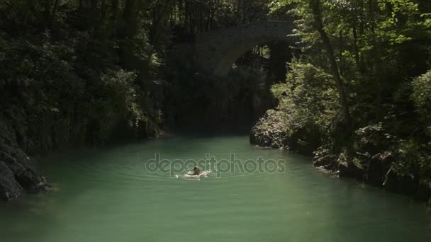 AERIALE: Bella donna sorridente che nuota nel rinfrescante fiume Soca nella giornata di sole — Video Stock