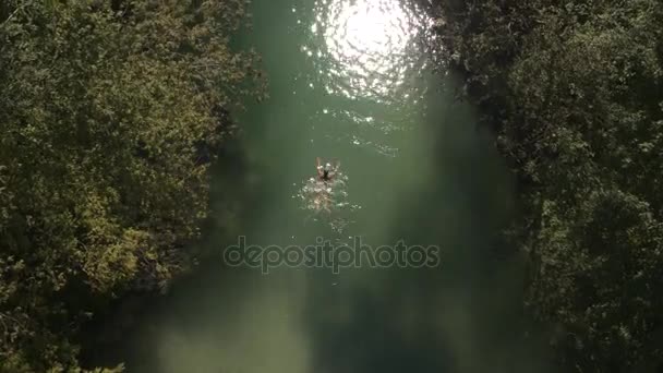 AERIAL: Mujer joven nadando en un río refrescante en el desierto en un día soleado — Vídeos de Stock