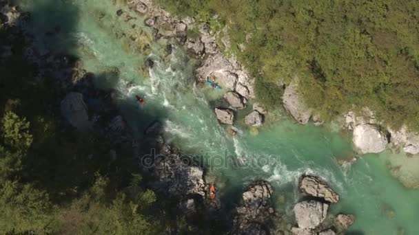 AERIAL: Remadores profesionales en kayak rojo, naranja y azul remando en el río de aguas bravas — Vídeo de stock
