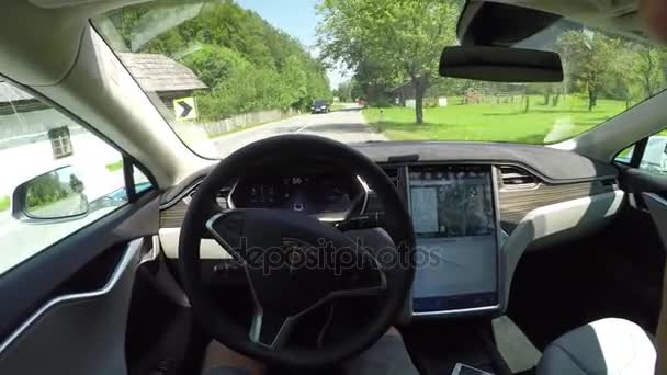 FPV: Tesla electric car self driving through green valley on local road — Stock Video