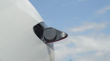 Yakın: lüks beyaz Tesla elektrikli otomobil güzel günde şarj genç adam