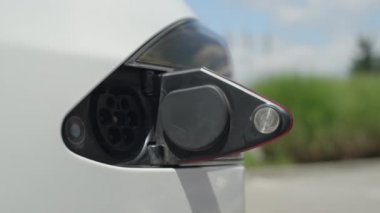 Yakın: İşadamı şarj lüks beyaz Tesla elektrikli otomobil güneşli