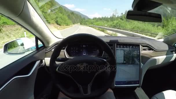 FPV: Tesla eco electric car self driving through green valley on local road — Stock Video