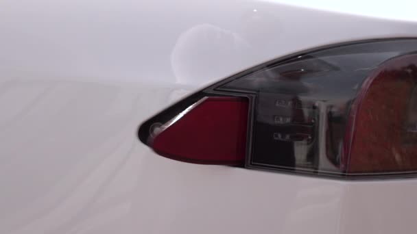 FECHAR UP: Jovem ligando Tesla carro elétrico branco na estação de carregamento — Vídeo de Stock