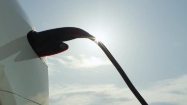 Yakın: güneşli gökyüzü altında doldurma batarya takılı Tesla özerk araba