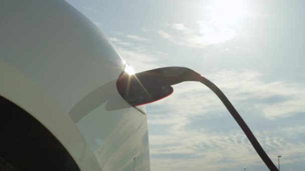 Nahaufnahme: Tesla-Elektroauto lädt Akkus unter sonnigem blauen Himmel auf — Stockvideo