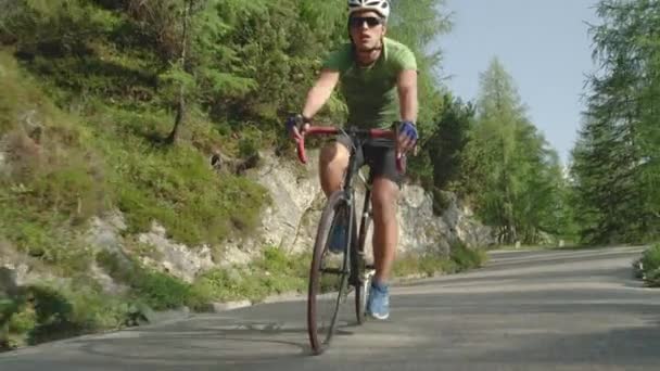 Zeitlupe: Junger Rennradfahrer rast mit seinem neuen Fahrrad die Forststraße hinunter. — Stockvideo