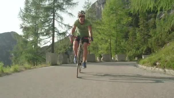 LOW ANGLE: Glada manliga väg cyklist njuter av en naturskön tur genom skogen. — Stockvideo