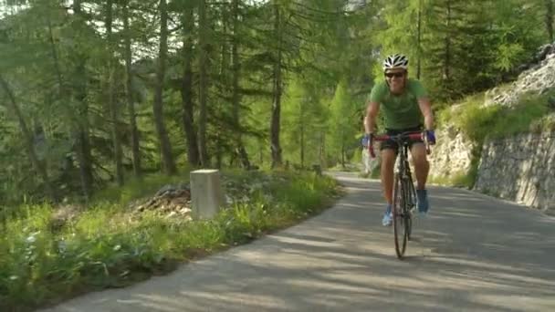 Slow Motion: Ung vägcyklist som har kul när han trampar uppför en brant asfalterad väg. — Stockvideo