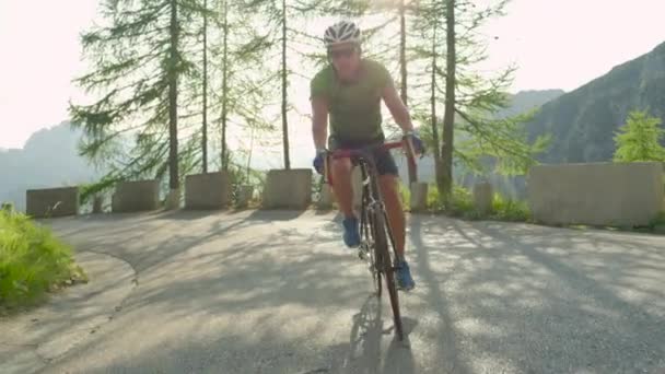 Αργή κίνηση: Χρυσές ηλιαχτίδες λάμπουν στο δρόμο του ανθρώπου ποδηλασία στα ηλιόλουστα βουνά. — Αρχείο Βίντεο