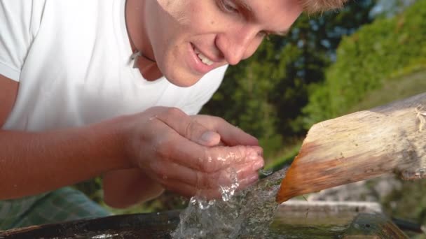 FECHAR-SE: Homem caucasiano alegre espirra água corrente pura e lava o rosto — Vídeo de Stock