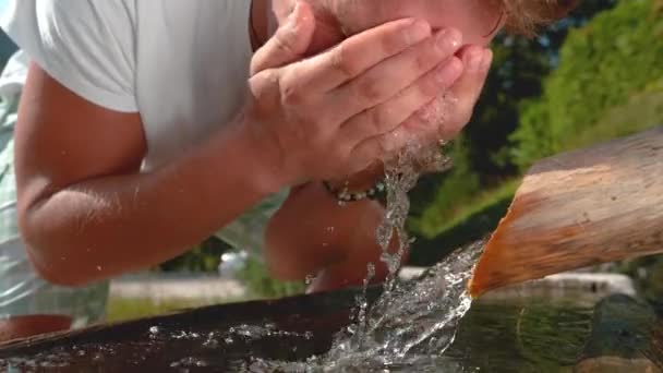 SLOW MOTION: Homem feliz lava o rosto com água refrescante do córrego da montanha . — Vídeo de Stock