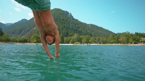 Αργή κίνηση: παιχνιδιάρικο αρσενικό τουρίστας πηδά στη λίμνη σε μια ζεστή καλοκαιρινή μέρα. — Αρχείο Βίντεο