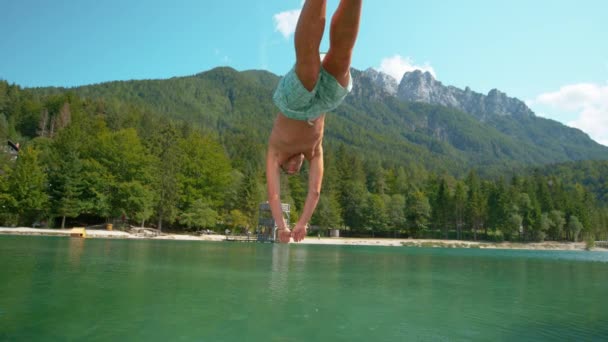 Pomalý pohyb: Aktivní mužské turistické skoky hlavou napřed do osvěžujícího jezera. — Stock video