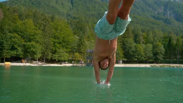 Timewarp: Atletisk manlig turist dyker ner i sjön omgiven av lummig skog. — Stockvideo