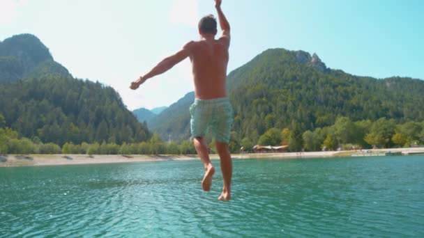 Медленное движение: Неузнаваемый человек убегает с пирса и прыгает в освежающее озеро — стоковое видео