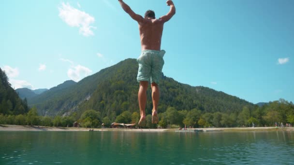 Pomalý pohyb: radostný kavkazský turista se ponoří do osvěžujícího smaragdového jezera. — Stock video