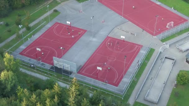 AERIAL: Volando alrededor de las concurridas canchas de baloncesto rojo en los suburbios de lujo . — Vídeo de stock