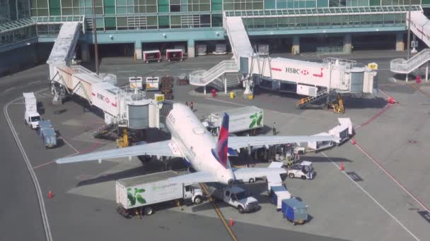 Timelapse: Duży samolot pasażerski Delta jest obsługiwany przez terminal przed wejściem na pokład. — Wideo stockowe