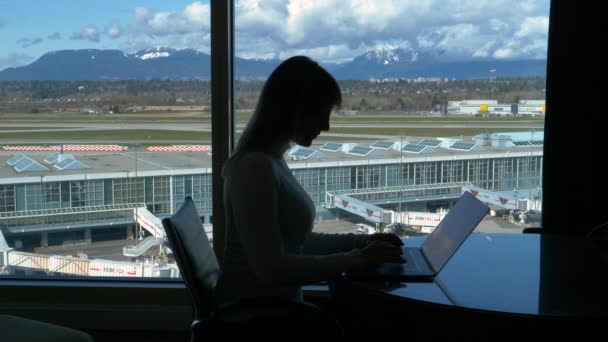 LEZÁRÁS: Fiatal üzletasszony dolgozik a laptopján, miközben várja a járatát — Stock videók