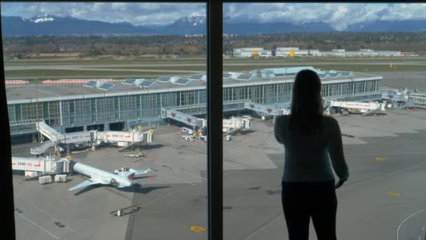 CERRAR: Mujer joven hablando en su teléfono celular mientras observa el aeropuerto . — Vídeo de stock
