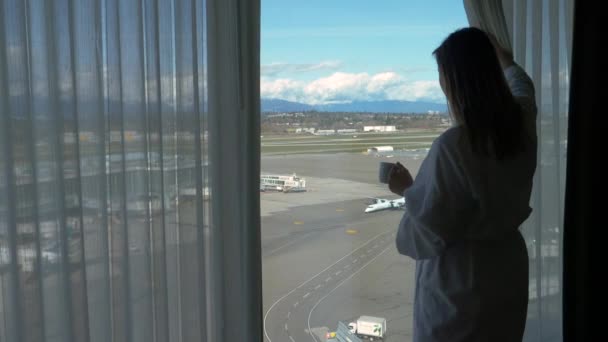 CLOSE UP: Woman drinks her morning coffee while observing the busy runway. — Stock Video