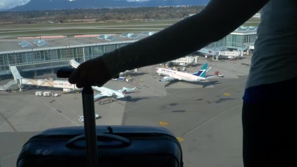 LOSE UP: Oigenkännlig kvinna håller sin resväska samtidigt observera flygplatsen. — Stockvideo