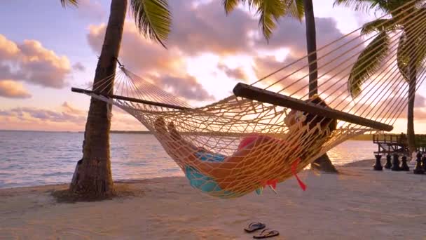 Young woman swaying on hammock swing under big tree at sunrise — Stock Footage Young Woman Swaying Hammock Swing Big Tree Sunrise Video Clip