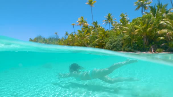 HALF IN HALF OUT: Niña despreocupada en el buceo de vacaciones en el tranquilo océano vidrioso . — Vídeo de stock