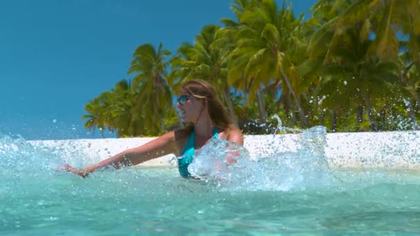 Sluiten omhoog: Speelse vrouw op vakantie spetteren het glazige water met haar handen. — Stockvideo